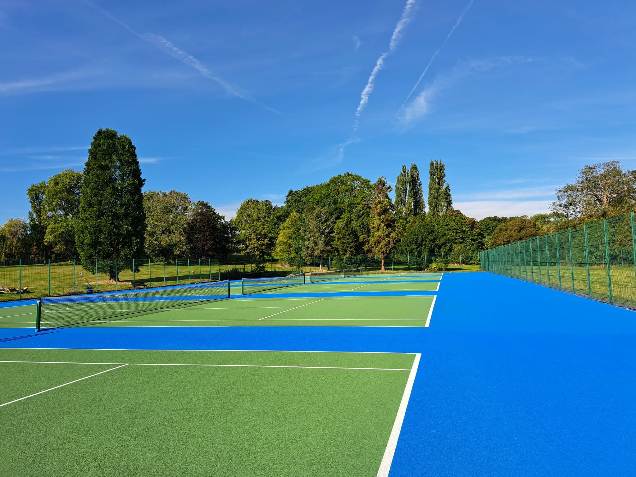 Blue and green hard tennis courts at Danson Park, Bexley, on a sunny day